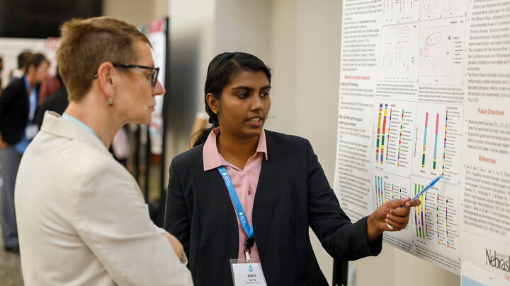 Two people talking in front of poster