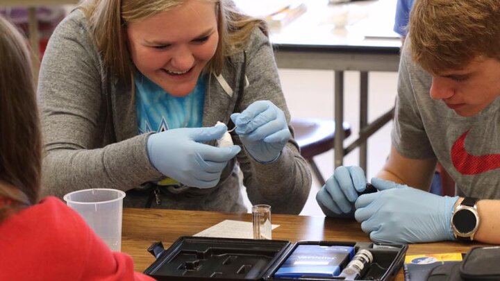 Person working with students with scientific equipment