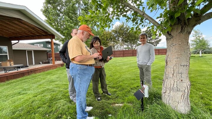 People standing in lawn looking at soil moisture sensor