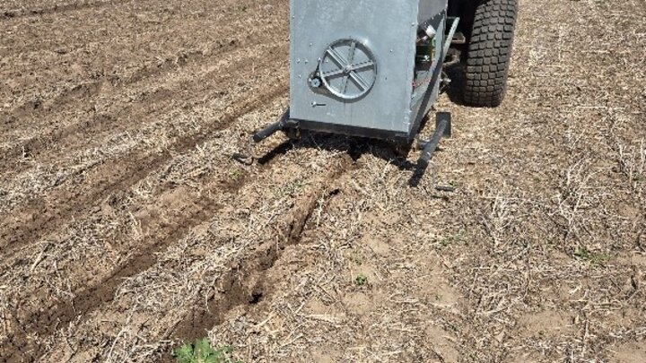 Farm auger hopping being pulled behind tractor in field