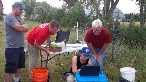 People working together in field and looking at laptop