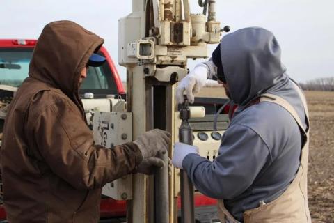 Two people working on well drilling equipment