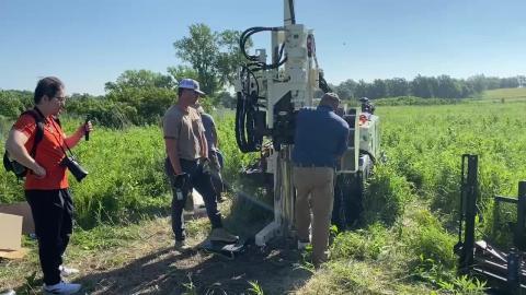 People working in field with well drilling