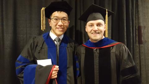 Two men standing together after receiving diploma